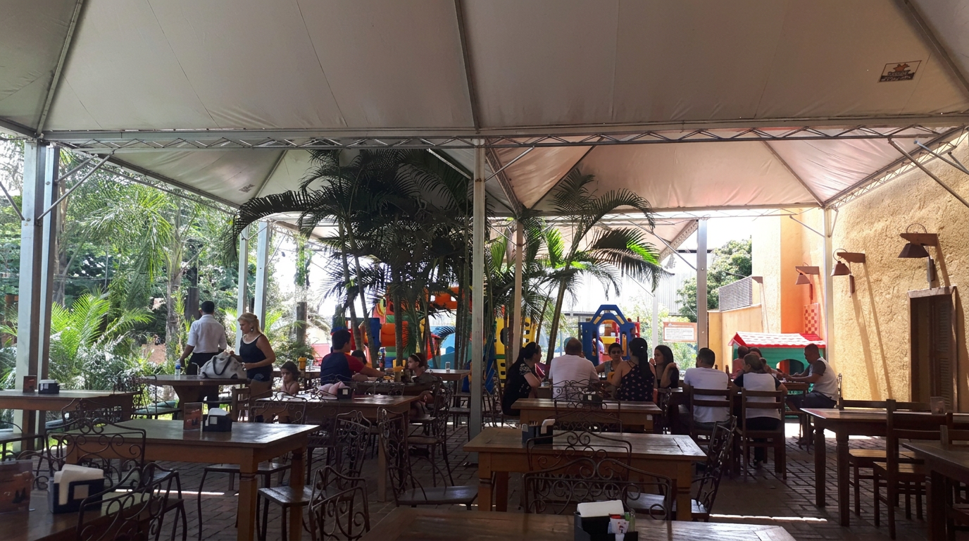 Área externa coberta do Restaurante Joá Villa Real com mesas, playground e vegetação