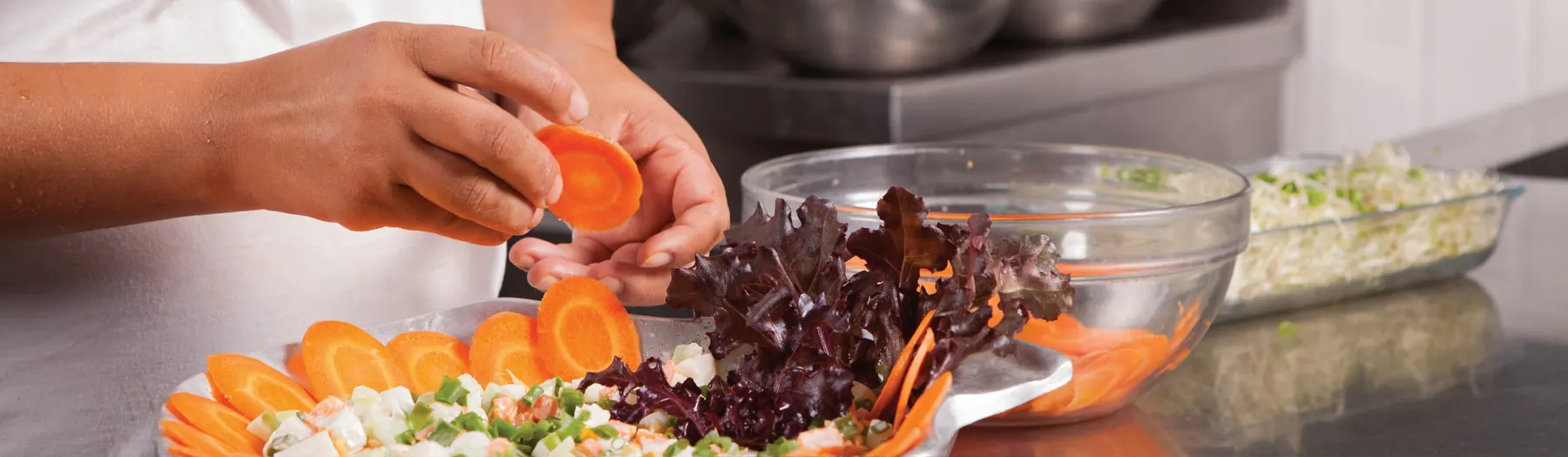 Bancada com saladas variadas prontas para servir na cozinha industrial de alimentação coletiva